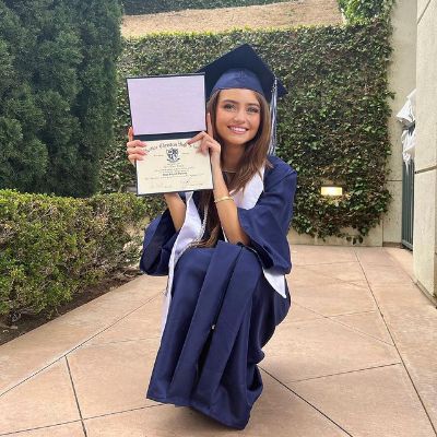 She is wearing a blue graduation gown while showing her degree.